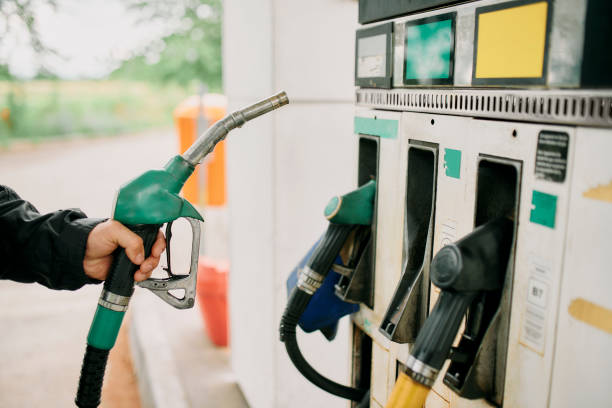 Hand, person or gas station with fuel gun, machine and transport cost for energy, pistol or petrol service. Closeup, gasoline or motor vehicle maintenance at garage to pump tank on road trip travel